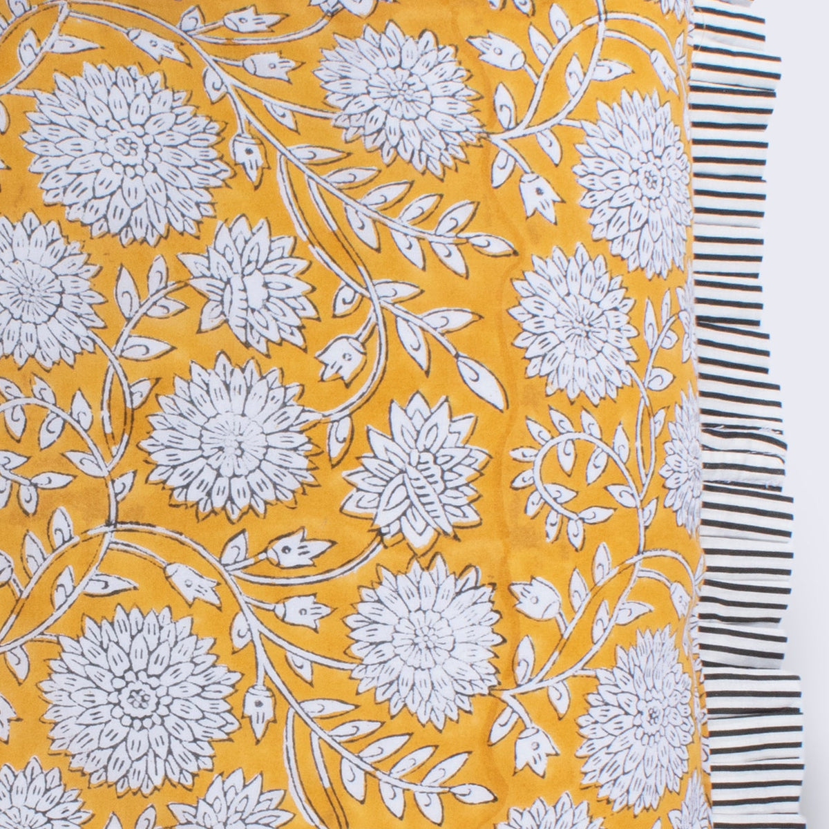 Hand Block Print Dahlia Cushion with Stripe Frill & Feather Insert – Saffron close-up detail showing the intricate hand block printed white dahlia blooms and trailing leaf motifs on vibrant saffron yellow cotton with the bold black and white candy stripe pleated frill edge