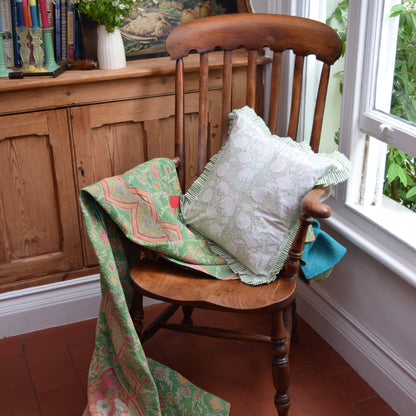 Hand Block Print Floral Cushion with Stripe Frill & Feather Insert – Muted Floral & Fauna lifestyle shot styled on a vintage wooden chair with a draped Kantha quilt, showing the faded mint green botanical floral cushion with green and white candy stripe pleated frill