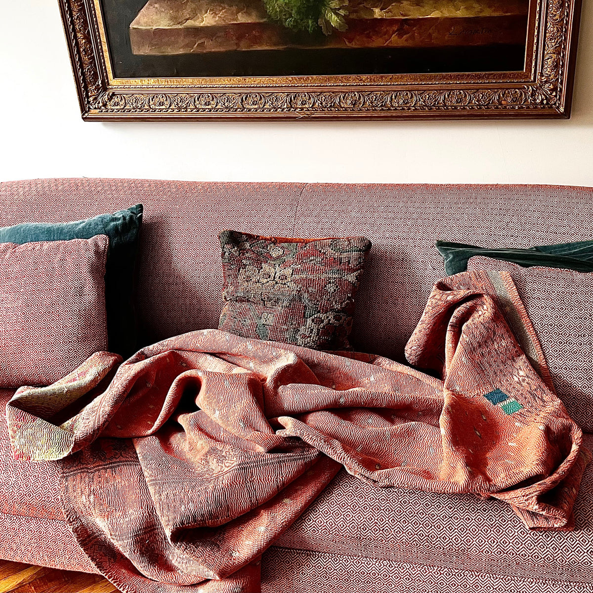 Handcrafted Vintage Kantha Quilt – Personality Patch draped over a sofa, showing pistachio, primrose and pink florals with distinctive personality patch detail