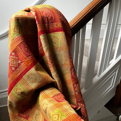 Handcrafted Vintage Kantha Quilt – Opal Fruit Leaves styled on a staircase, showing faded pink, burnt orange and lime green with intricate purple stitching