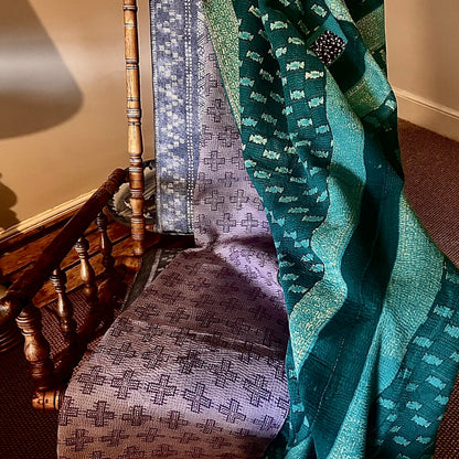 Handcrafted Vintage Kantha Quilt – Purple Aqua Ocean Haze lifestyle scene draped over a vintage wooden rocking chair showing both reversible sides — soft purple cross motif and rich ocean teal with decorative Kantha stitching